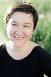 White woman with short black hair and brown eyes smiling (portrait)