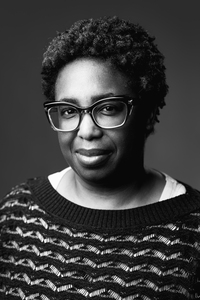 Black and white headshot of Alexis Wright, a Black woman with short natural hair and glasses, wearing a textured sweater and looking calmly at the camera.