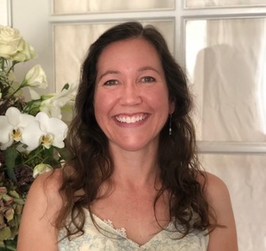 photo of a woman smiling beside flowers