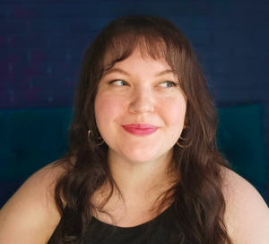 Laurel Holl, a fat white woman with brown hair smiles and looks to the right.
