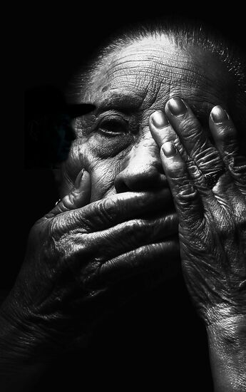 an elderly woman with a hand on her face and creepy shadow by her head