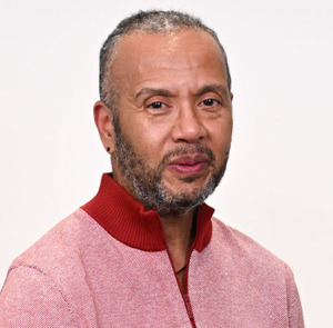 Black man with salt and pepper beard in a red sweater.