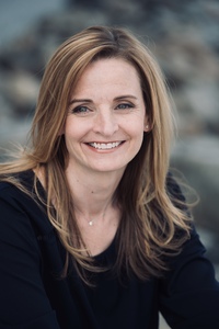 A woman with dark blond hair and a navy blue shirt facing the camera and smiling. 