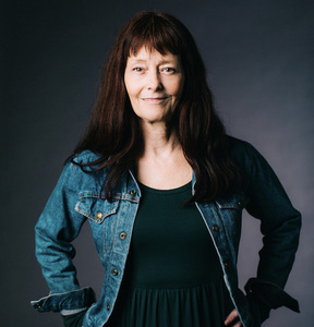 Author Cyndi Perkins in a professional portrait wearing a green dress and denim jacket 