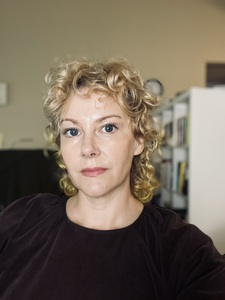 photo of author sitting in front of a bookshelf