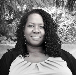 smiling brown skinned woman with locs 