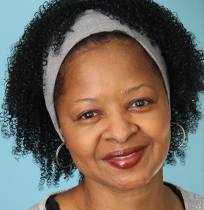 Headshot of writer Hermione Beard smiling with a gray headband and a natural textured hair style.
